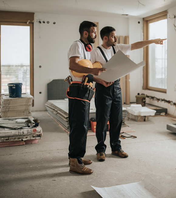 two men in construction gear discuss plan for room renovation